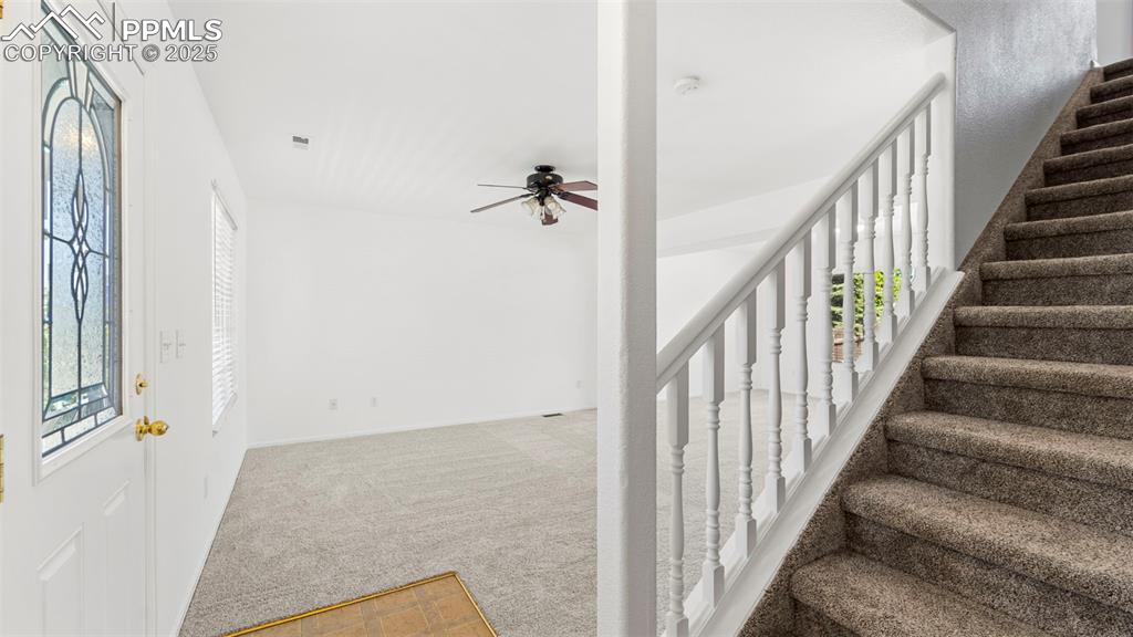 Image 19 of 46: Entrance foyer featuring stairs, carpet, and ceiling fan