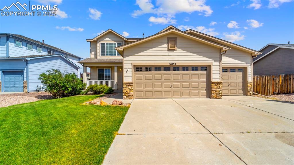 Image 2 of 46: View of front of home featuring stone siding, concrete driveway, an three a