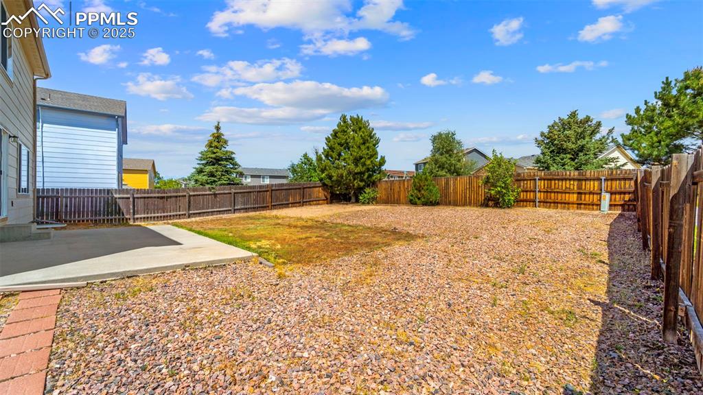 Image 38 of 46: Fenced backyard with a patio