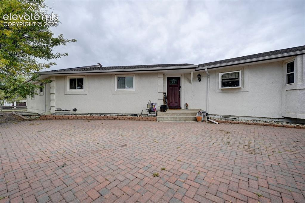 Image 1 of 50: Brick paver driveway leading to a stucco exterior with multiple windows and