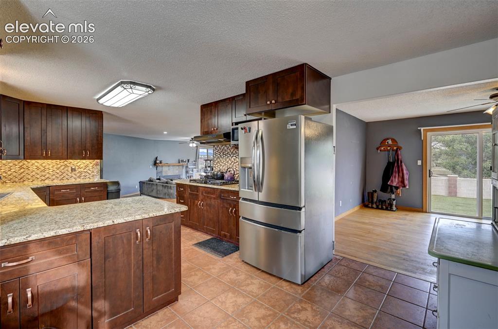 Image 10 of 50: Kitchen featuring stainless steel appliances, wood-finish cabinetry, stone 