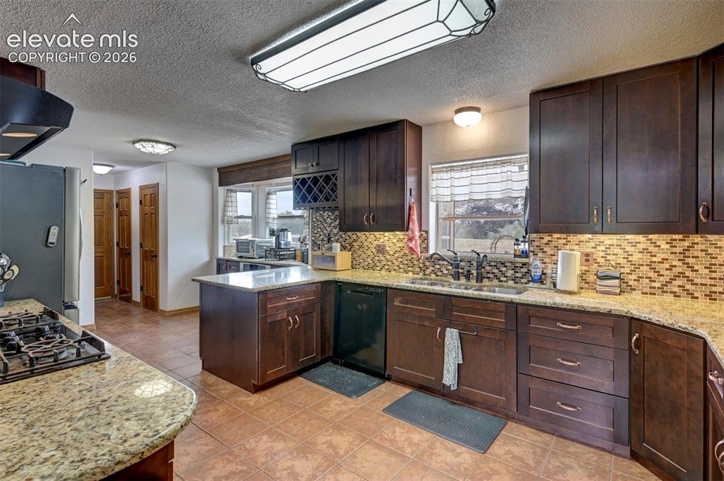 Image 12 of 50: Kitchen featuring wood-finish cabinetry, granite countertops, tile flooring