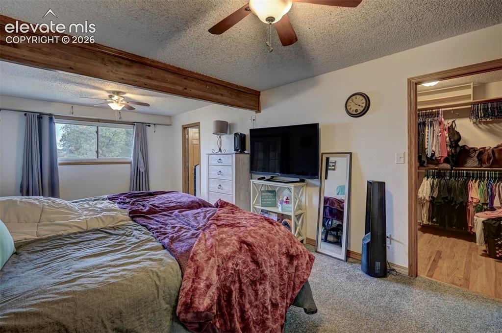 Image 13 of 50: Exposed wood ceiling beam, ceiling fan, window with exterior scenery, carpe