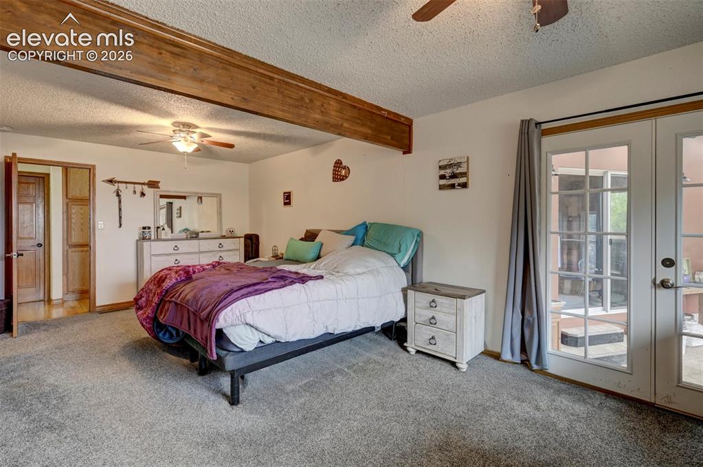 Image 15 of 50: Carpeted room with exposed wood beam, ceiling fan with light fixture, and F
