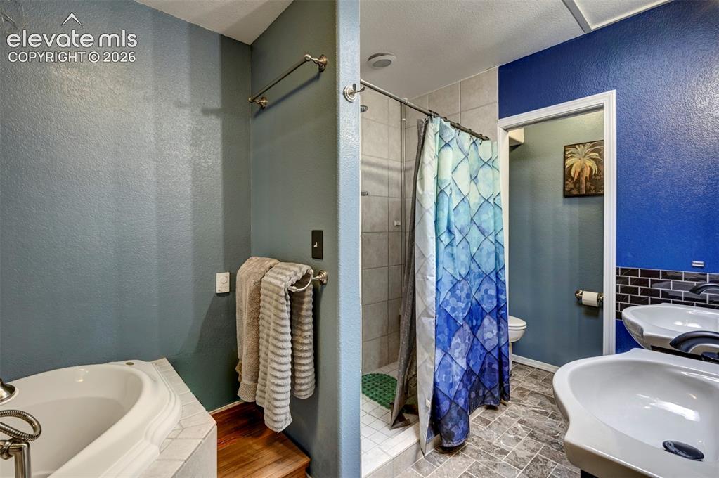 Image 18 of 50: Built-in soaking tub with tiled surround, walk-in shower with tiled walls, 