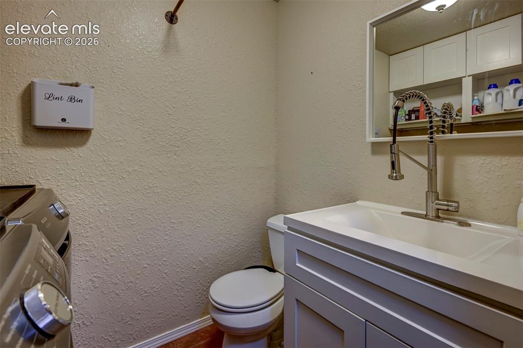 Image 19 of 50: Vanity with integrated sink, pull-down faucet, wall-mounted mirror, and whi