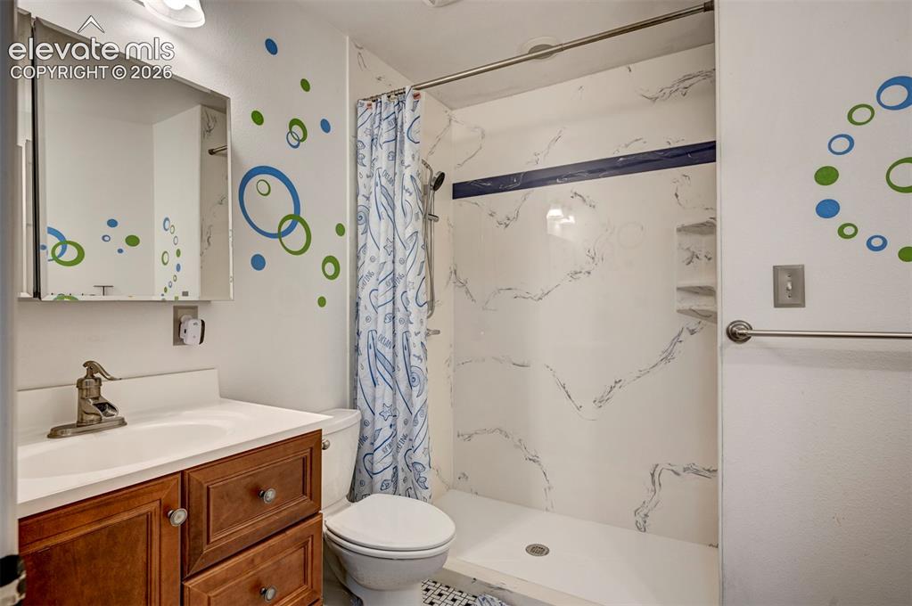 Image 22 of 50: Vanity with wood-finish cabinetry, white countertop, and integrated sink
