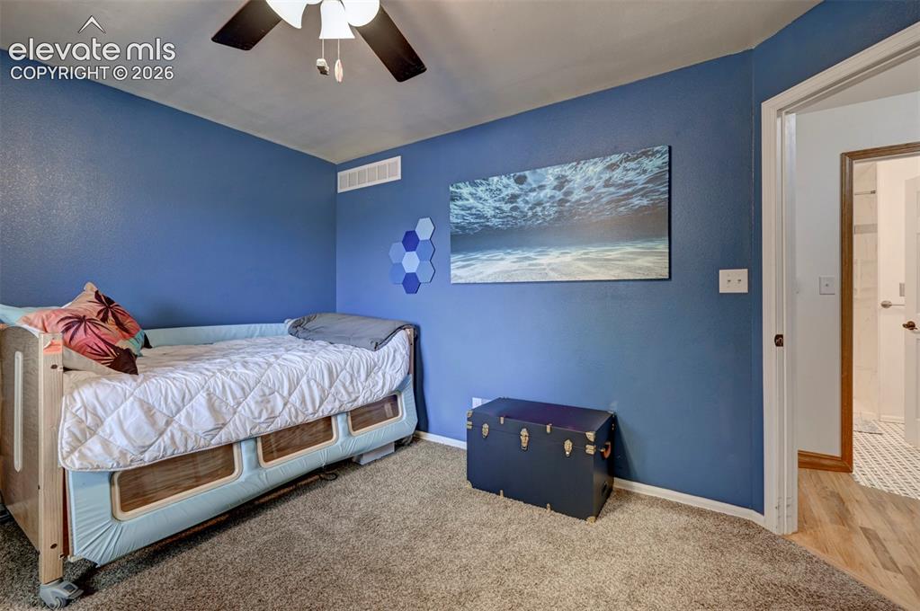 Image 24 of 50: Carpeted flooring, blue painted walls, and a ceiling-mounted fan with integ