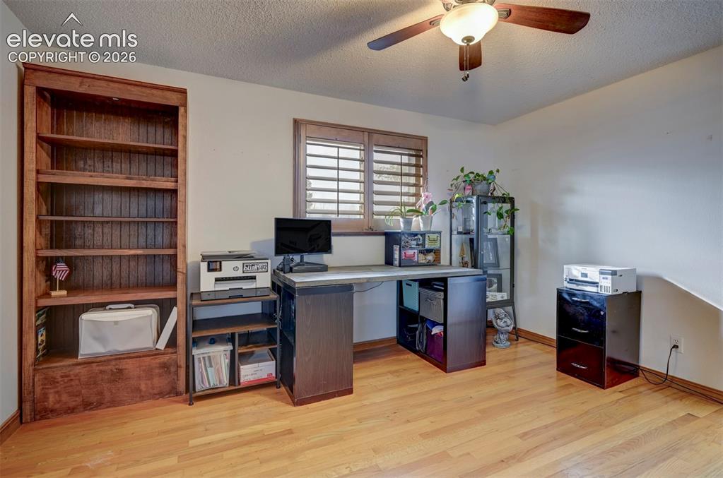 Image 25 of 50: Hardwood flooring, wood-finish built-in shelving, window with plantation sh