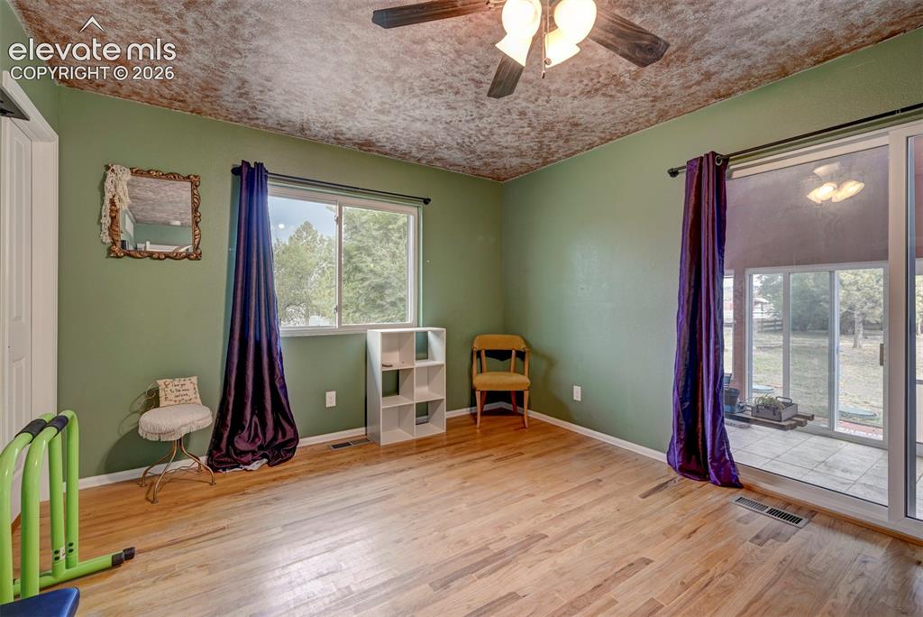 Image 27 of 50: Wood-finish flooring with a ceiling fan light fixture