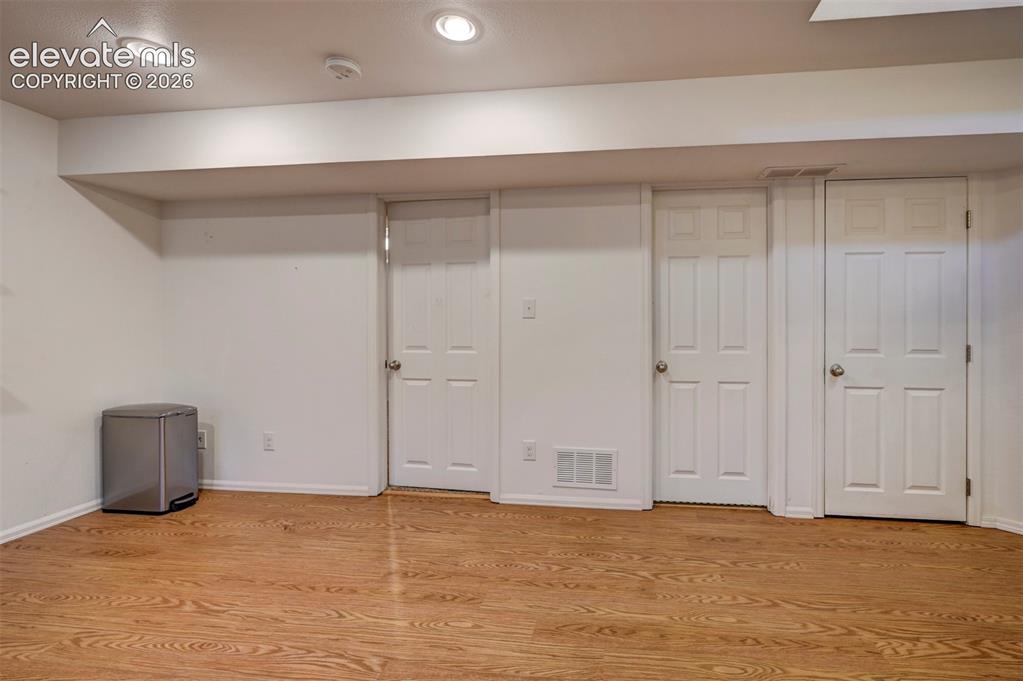 Image 28 of 50: Wood-finish flooring with recessed lighting, multiple paneled doors, and wh