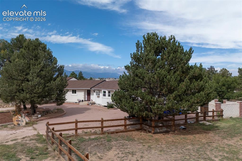 Image 3 of 50: Spacious property featuring mature evergreen trees, a split-rail fence, and