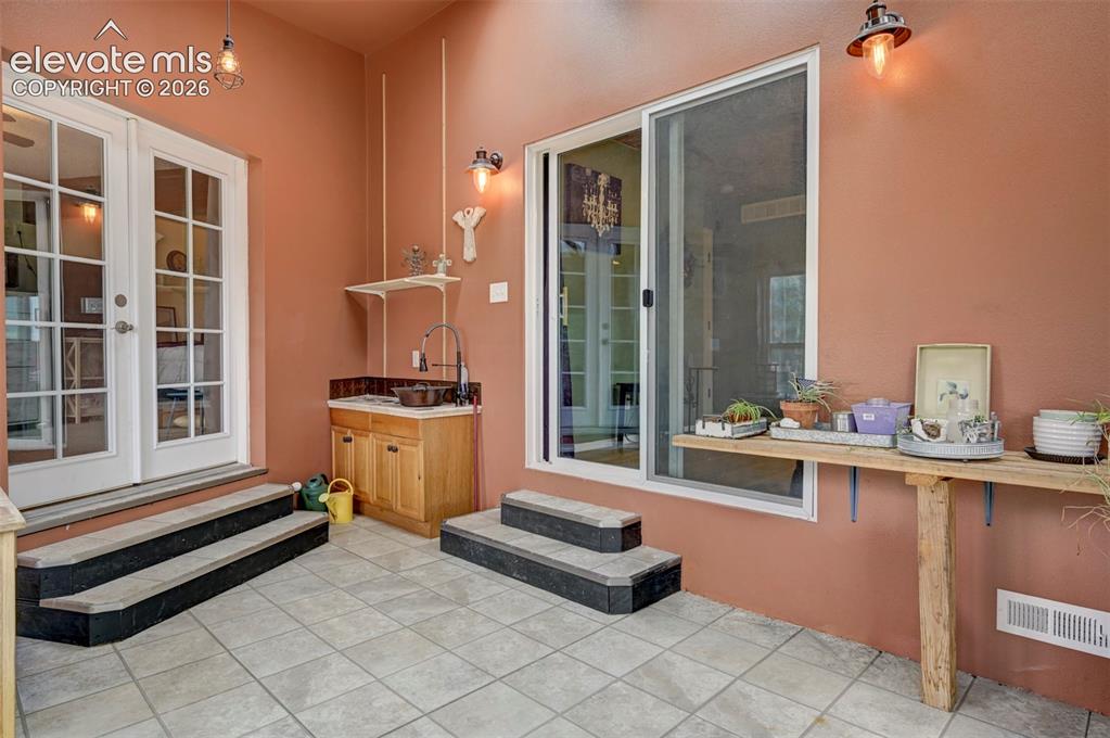 Image 32 of 50: Tiled flooring with a built-in wet bar, wood-finish cabinetry, and a slidin