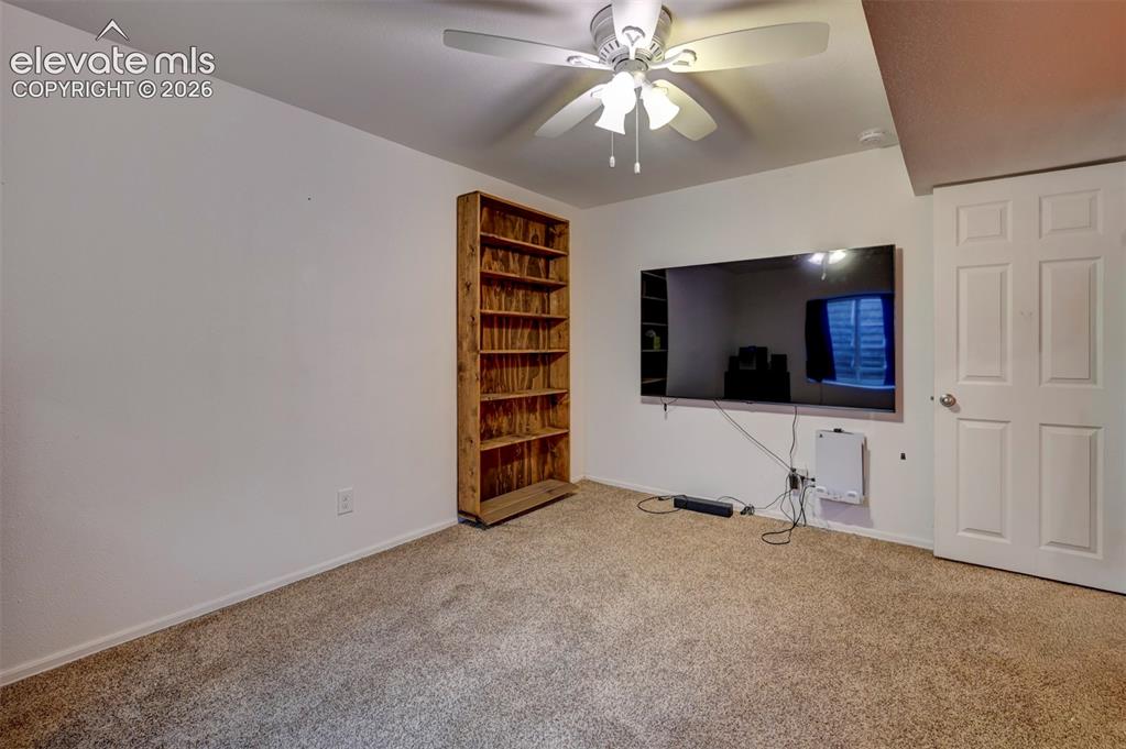 Image 34 of 50: Recessed wall-mounted television, built-in wooden shelving, and ceiling fan