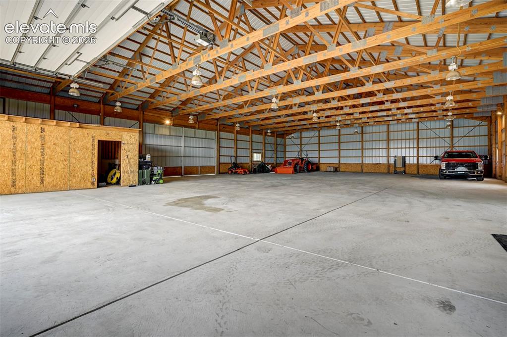 Image 37 of 50: Expansive concrete floor, exposed wood beam ceiling, metal roof, multiple o