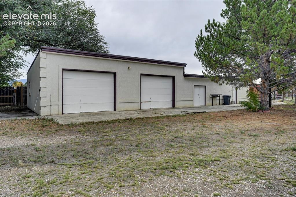 Image 39 of 50: Stucco exterior structure featuring two garage doors and a separate entry d
