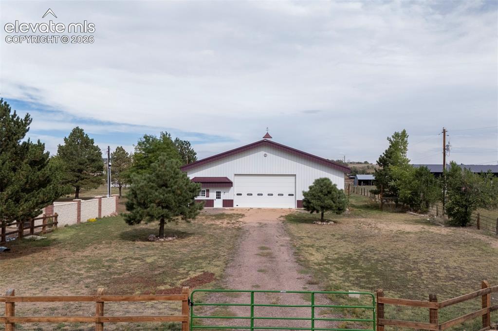 Image 4 of 50: Expansive building with white siding and a red roof, featuring a large gara