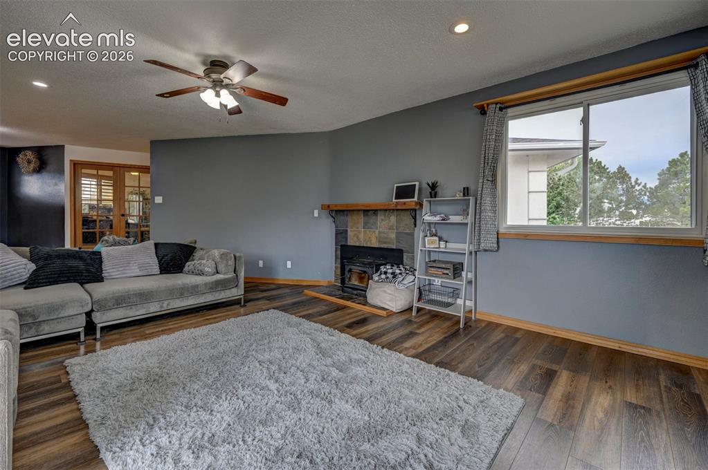 Image 6 of 50: Wood-finish flooring, ceiling fan, recessed lighting, fireplace with stone