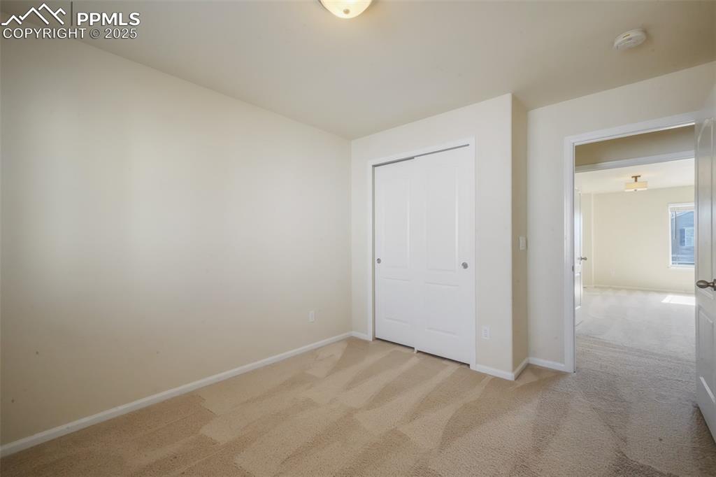 Image 29 of 50: Unfurnished bedroom with baseboards, a closet, and light colored carpet
