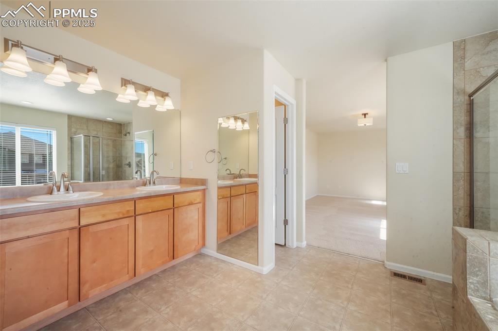 Image 36 of 50: Bathroom with double vanity, a sink, visible vents, and a shower stall