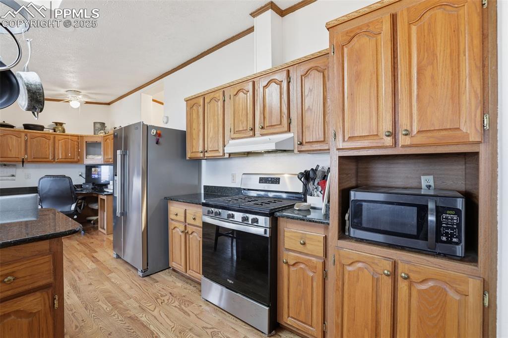 Image 14 of 49: Kitchen with ornamental molding, stainless steel appliances, light wood-sty