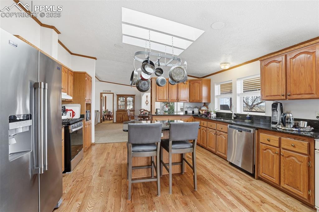 Image 15 of 49: Kitchen with stainless steel appliances, brown cabinets, a breakfast bar ar