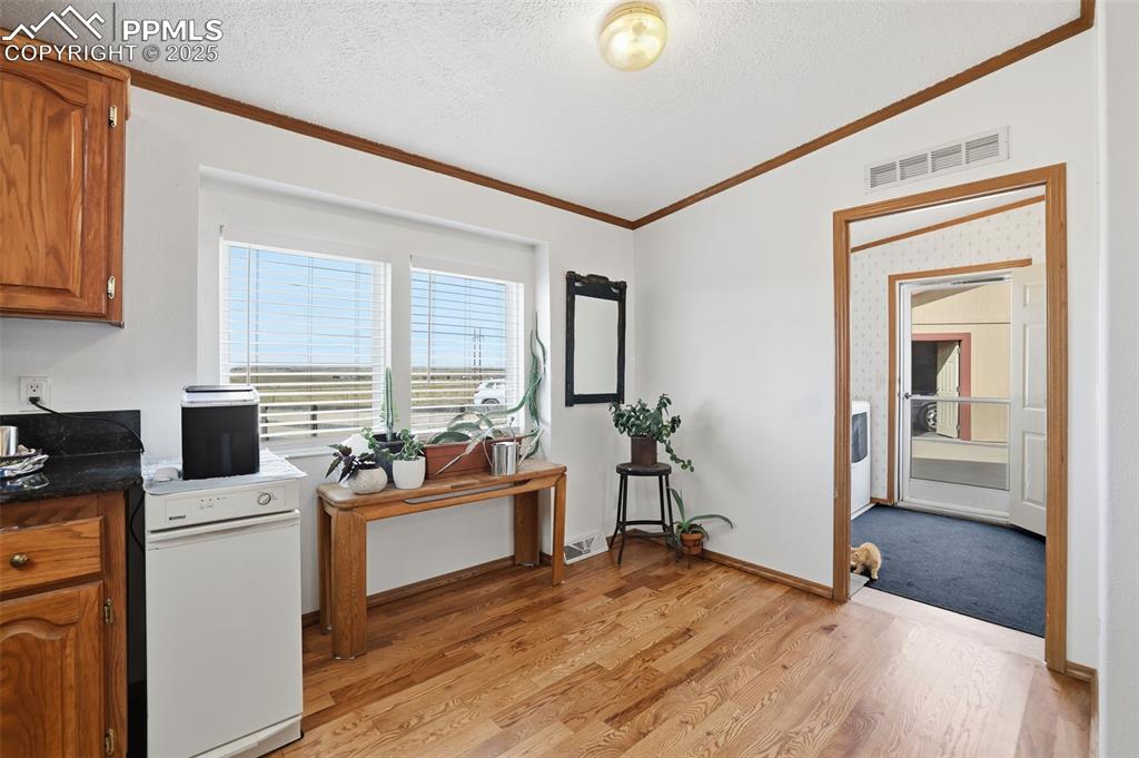 Image 16 of 49: Kitchen featuring brown cabinetry, a textured ceiling, vaulted ceiling, dar