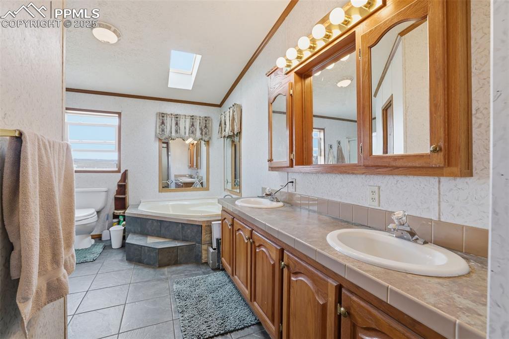 Image 21 of 49: Full bath featuring a skylight, a bath, double vanity, ornamental molding, 