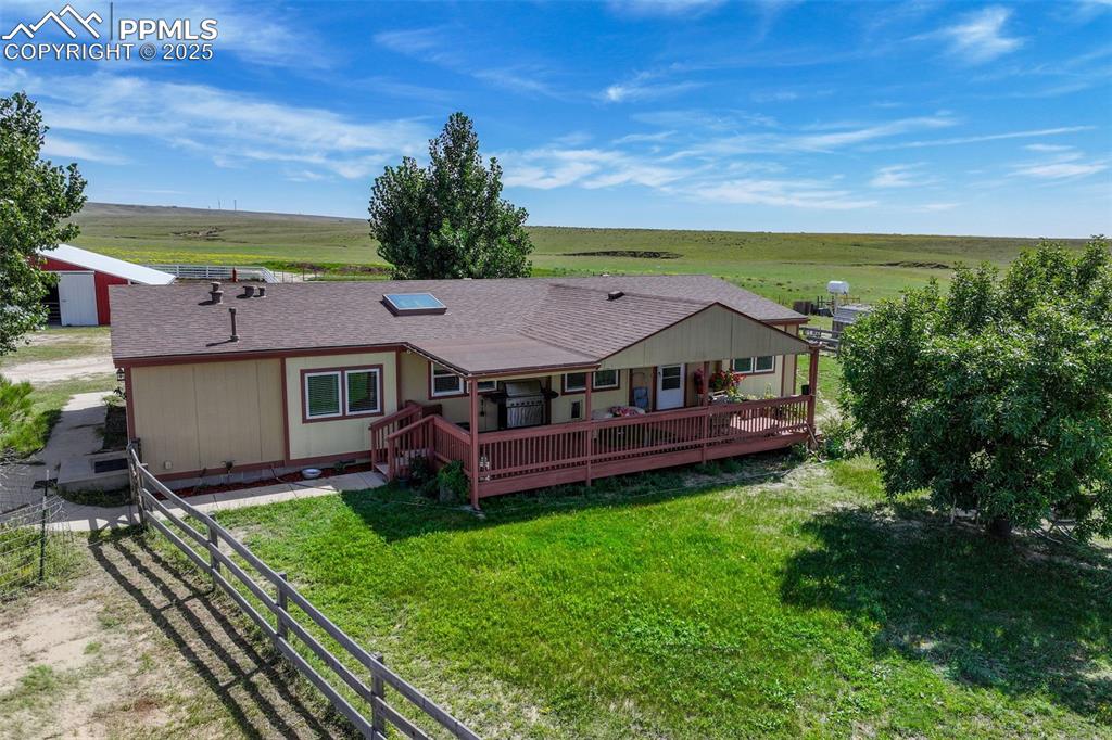 Image 4 of 49: Back of property featuring a shingled roof, a rural view, and a wooden deck