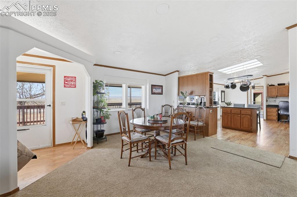 Image 8 of 49: Dining room featuring light wood-style flooring, crown molding, and a textu