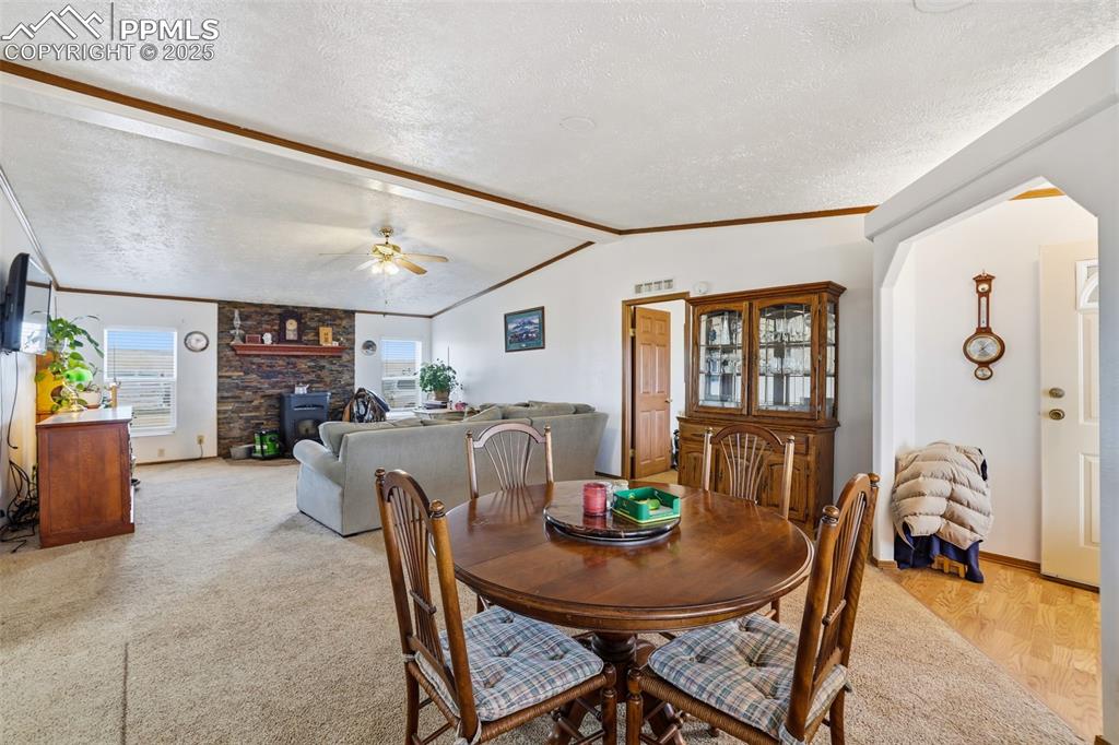 Image 9 of 49: Dining area with a textured ceiling, a wood stove, crown molding, and a cei