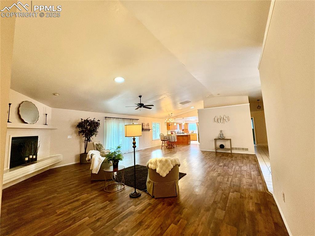Image 11 of 27: Living area with a fireplace with raised hearth, dark wood-type flooring, l