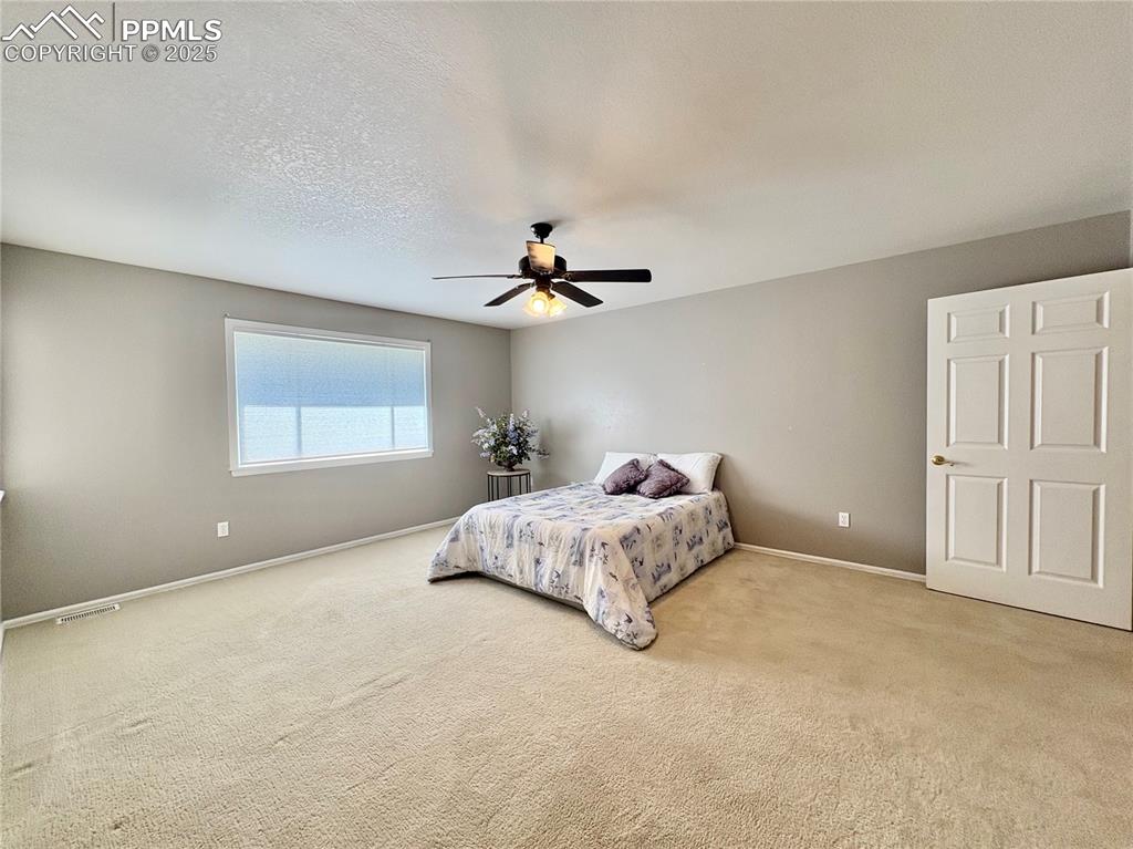 Image 15 of 27: Carpeted bedroom with a ceiling fan and a textured ceiling
