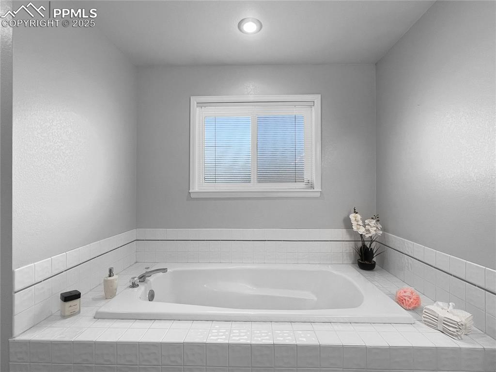 Image 17 of 27: Full bathroom with a bath and a textured wall