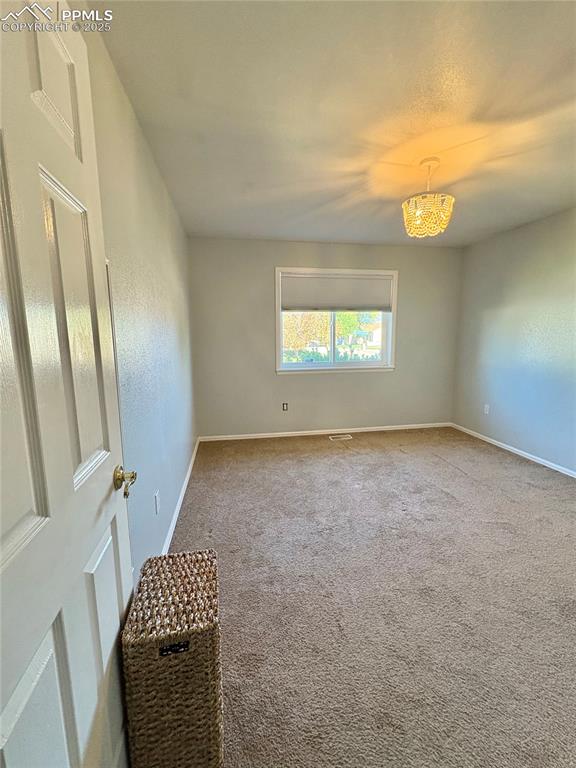 Image 22 of 27: Carpeted empty room featuring baseboards and a chandelier