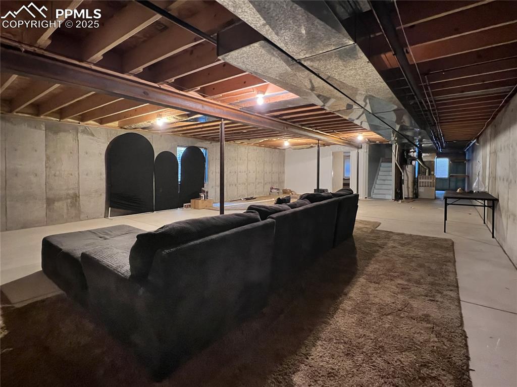 Image 24 of 27: Unfinished basement with stairs and water heater