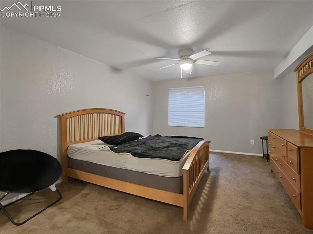 Image 25 of 27: Carpeted bedroom with ceiling fan and baseboards