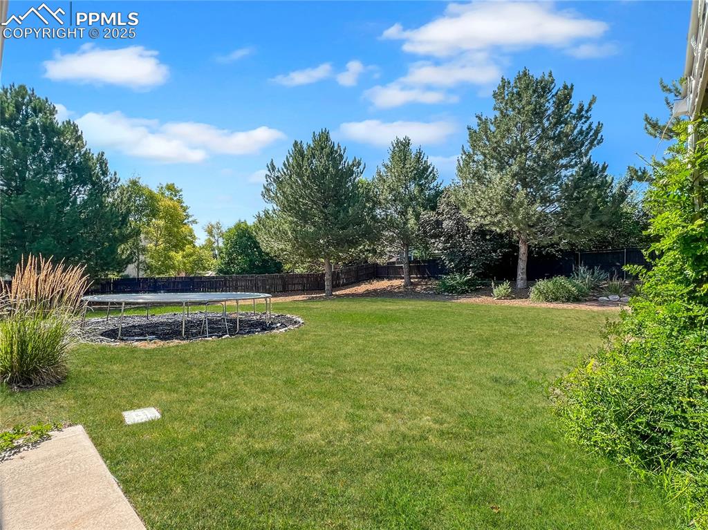 Image 4 of 27: Fenced backyard with a trampoline