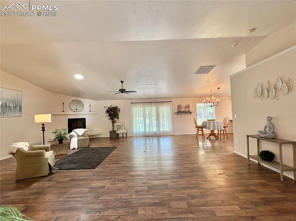 Image 9 of 27: Living room featuring a ceiling fan, dark wood-style flooring, a chandelier