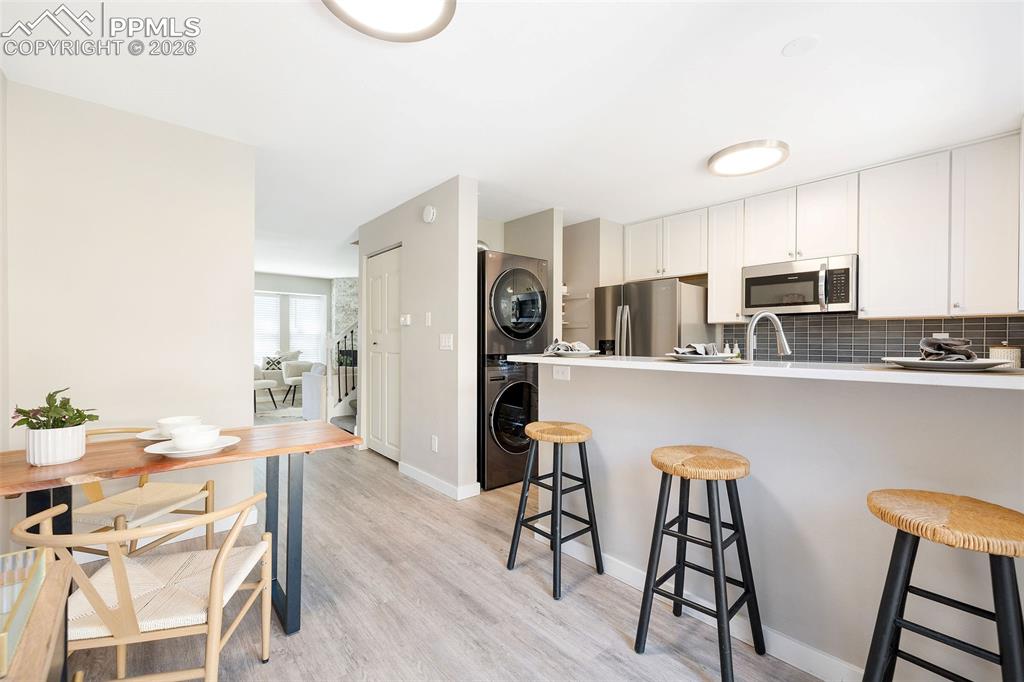 Image 10 of 26: Kitchen and dining area featuring light wood-finish flooring, white cabinet