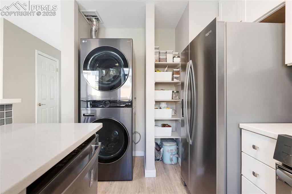 Image 12 of 26: Kitchen area featuring a stacked stainless steel washer and dryer, stainles