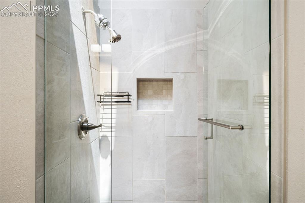 Image 18 of 26: Glass-enclosed shower featuring large format tile, a built-in niche with mo