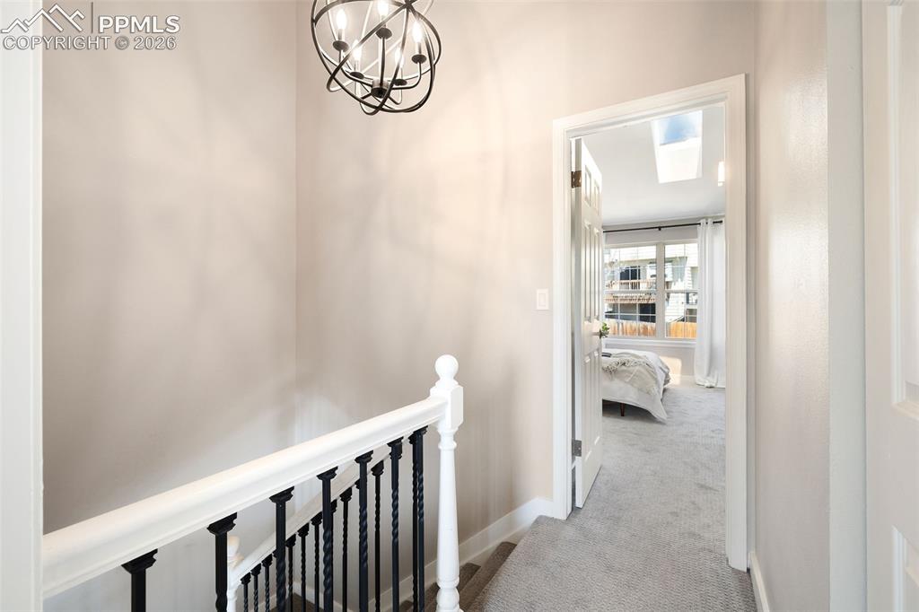Image 19 of 26: Staircase landing with a contemporary black orb chandelier, white painted b