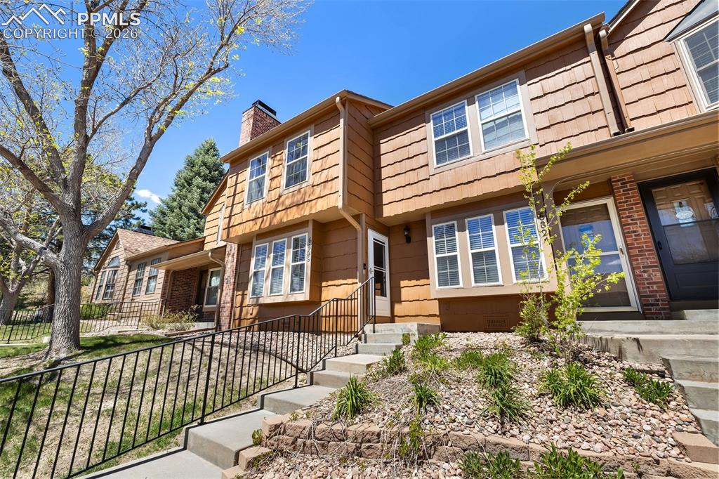 Image 2 of 26: Townhome exterior featuring cedar shake siding, brick accents, and concrete