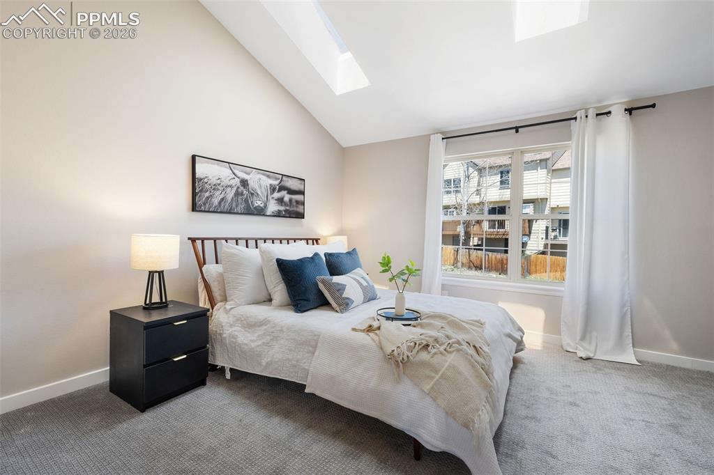 Image 20 of 26: Vaulted ceiling bedroom with two skylights, a large multi-pane window, and 