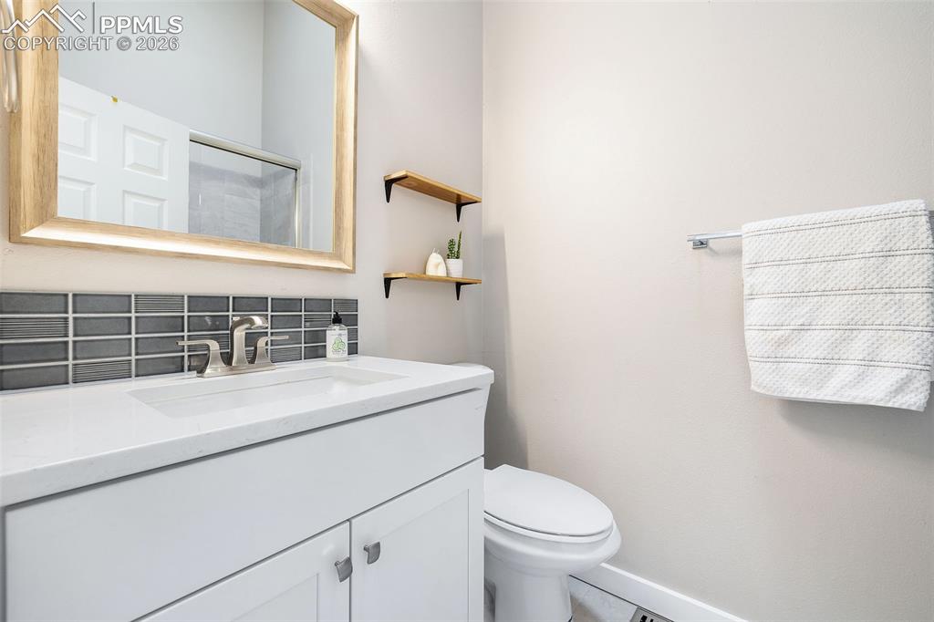 Image 23 of 26: Bathroom featuring a white vanity with integrated sink, modern faucet, and 
