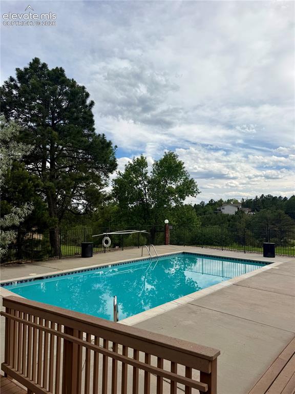 Image 28 of 30: Outdoor swimming pool with concrete decking, surrounded by mature trees