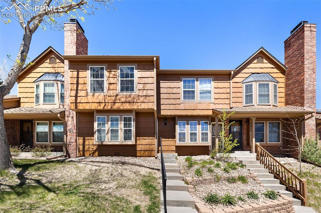 Image 3 of 26: Multi-level townhome exterior featuring shingle siding, prominent brick chi