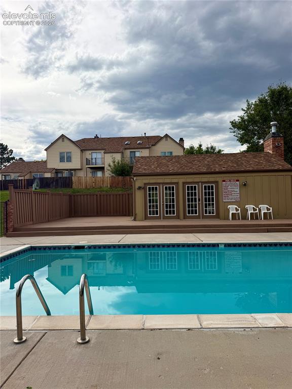 Image 30 of 30: Outdoor swimming pool with concrete surround, featuring metal ladder rails,