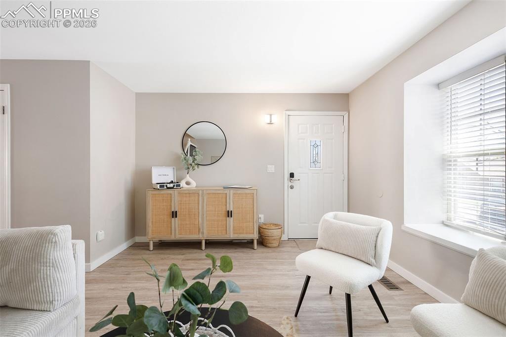 Image 5 of 26: Entry area with wood-finish flooring, neutral wall paint, and a white front
